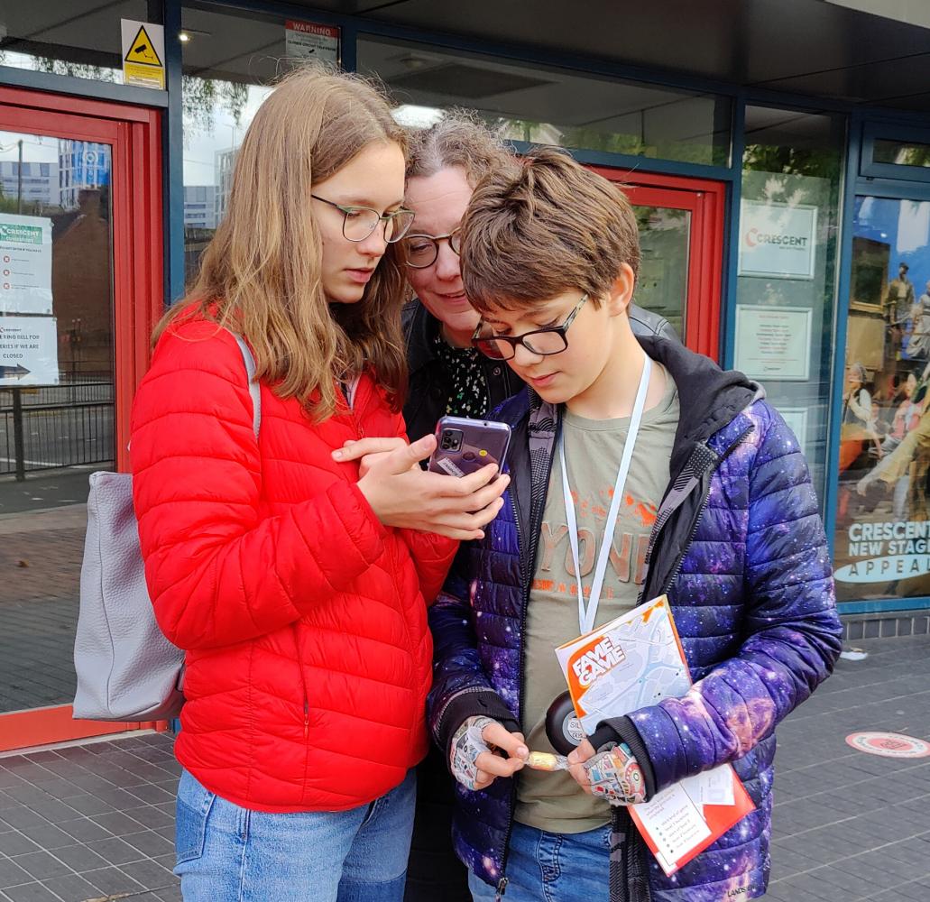 Photograph of a family playing Fame Game on a shared mobile device
