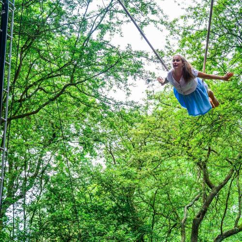 a woman on a large swing high up in trees
