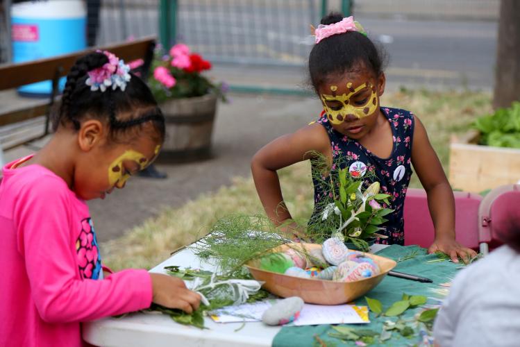 Children take part in craft activities using painted rocks and foliage.