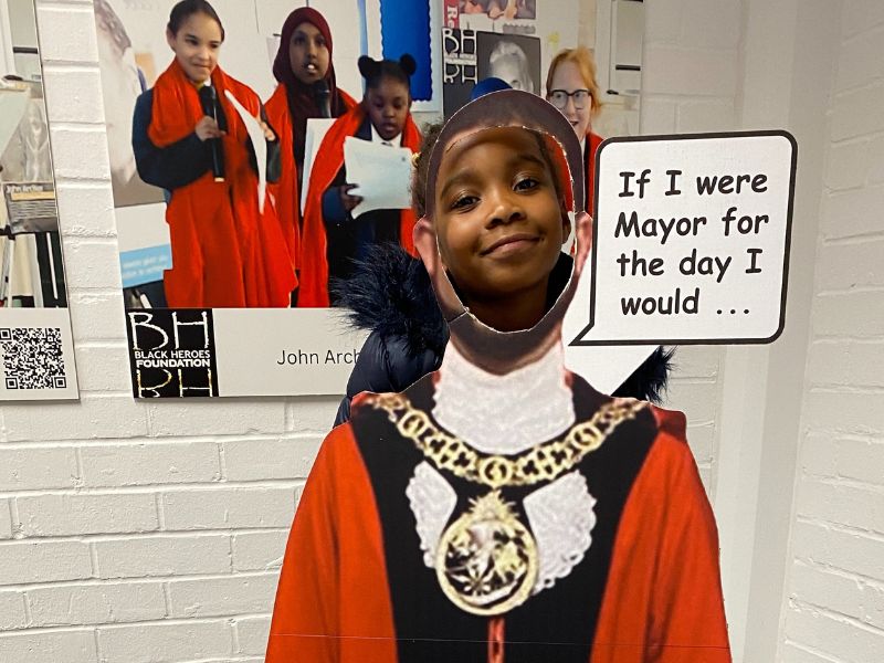 Child with head in picture of the Mayor, saying