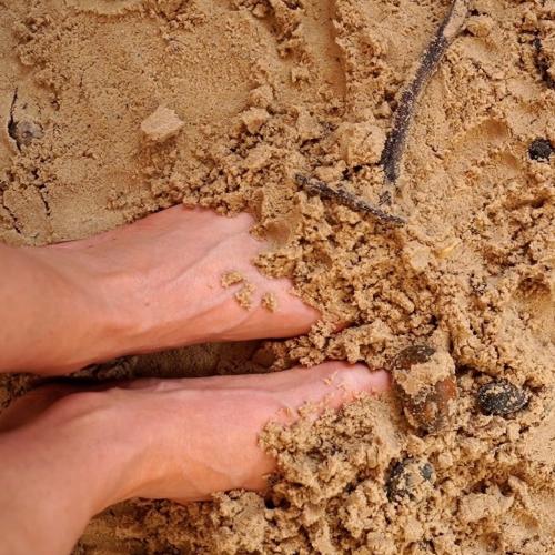 Feet half-buried in sand