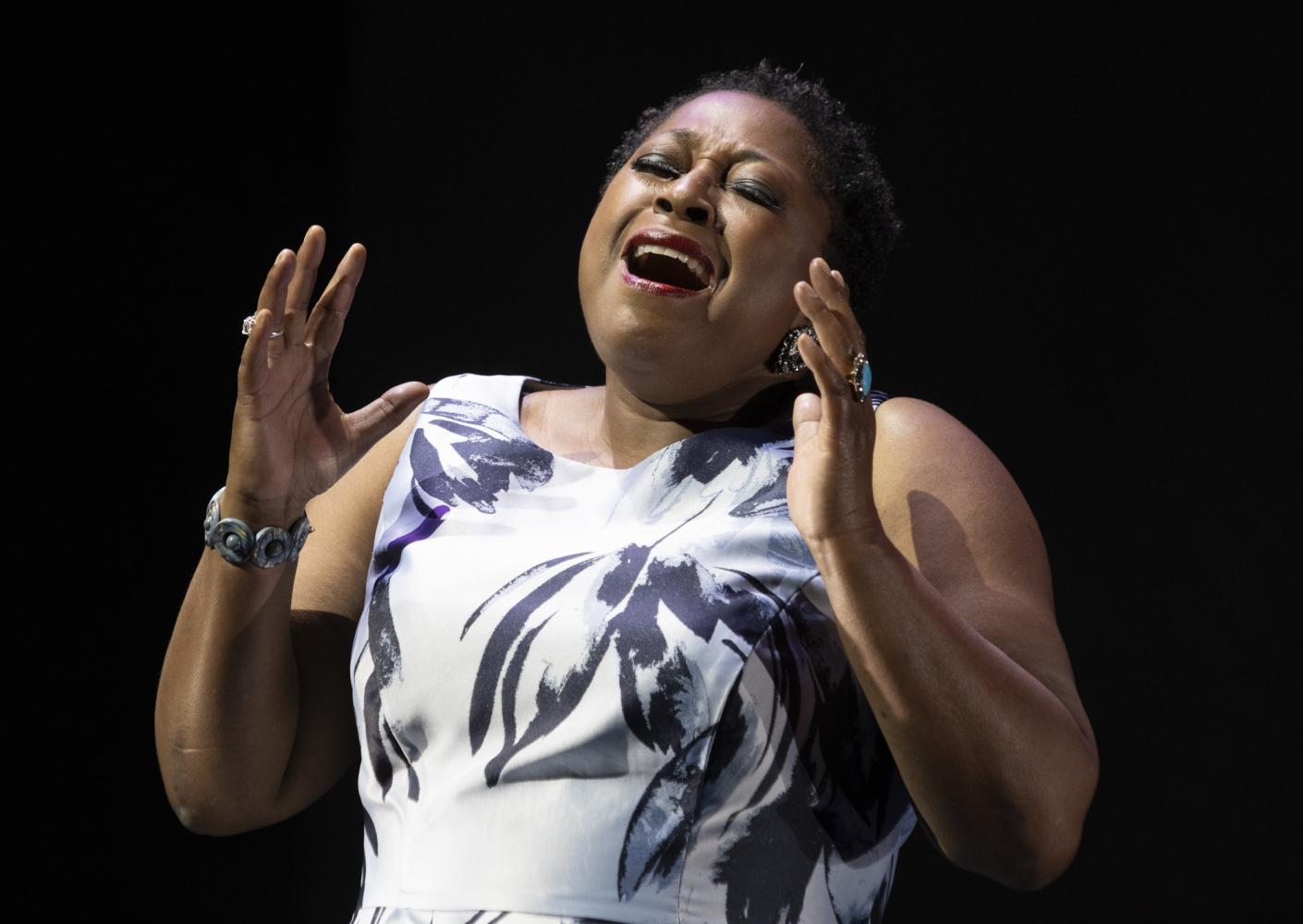 Alison Buchanan, black female opera singer, singing a song in a white and black dress