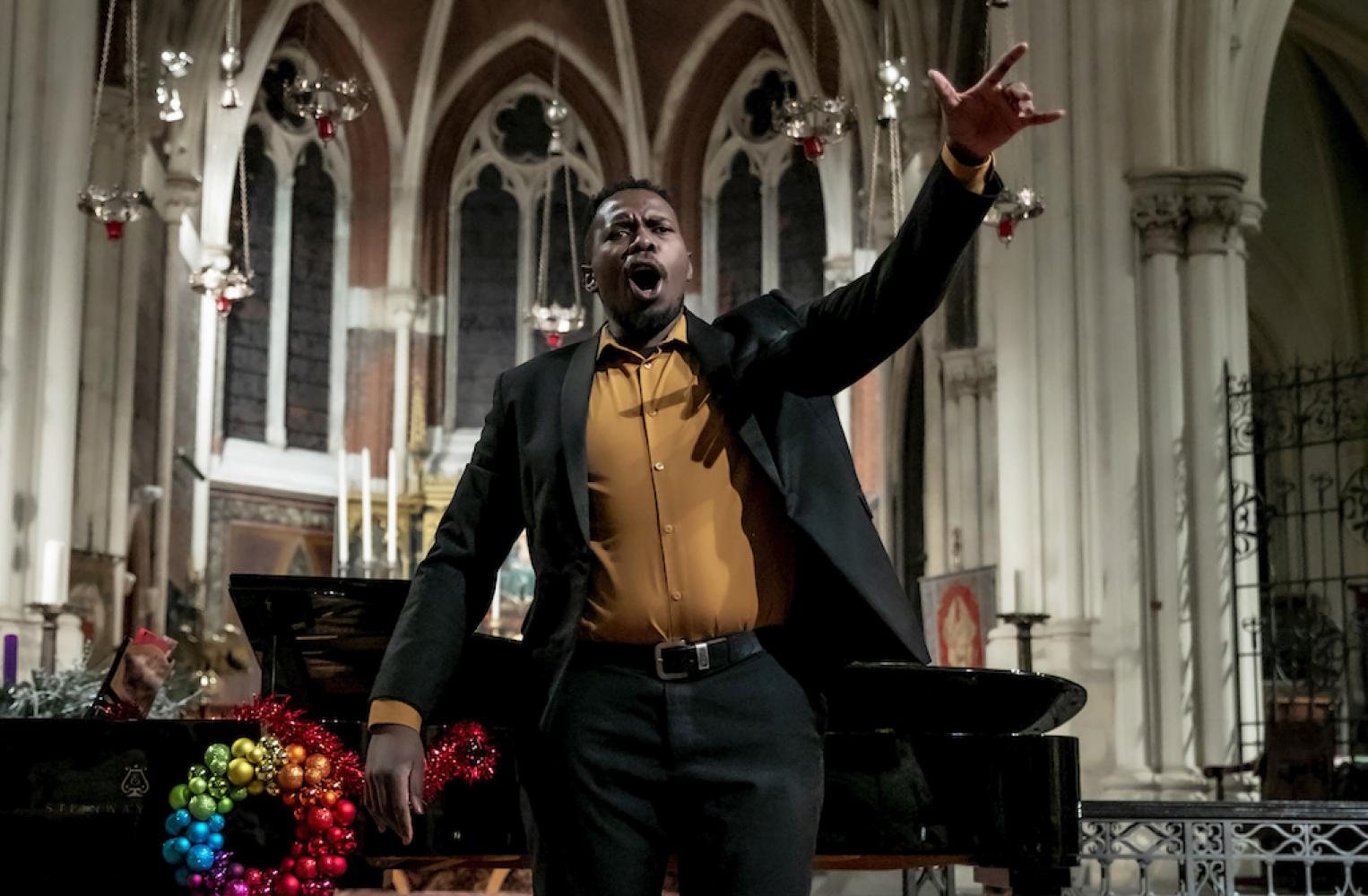 black male opera singer, singing with arm out stretched