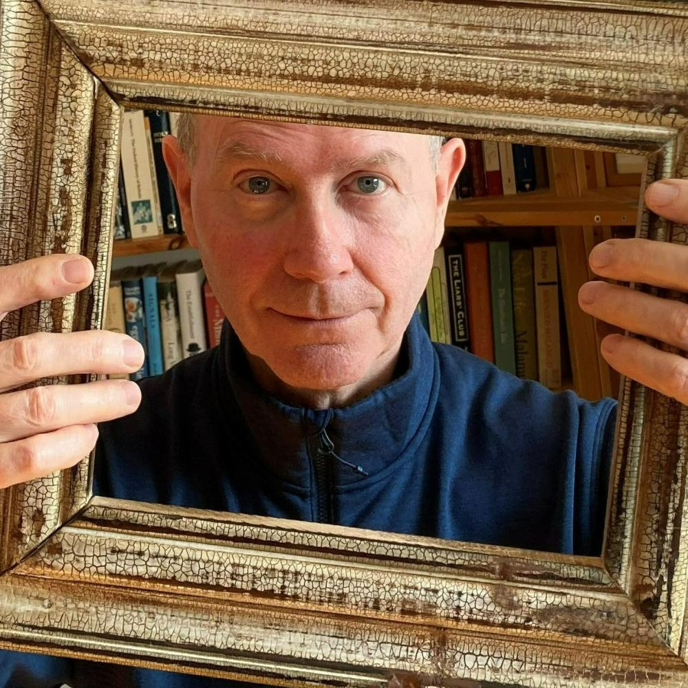 Elderly White man looking through a picture frame