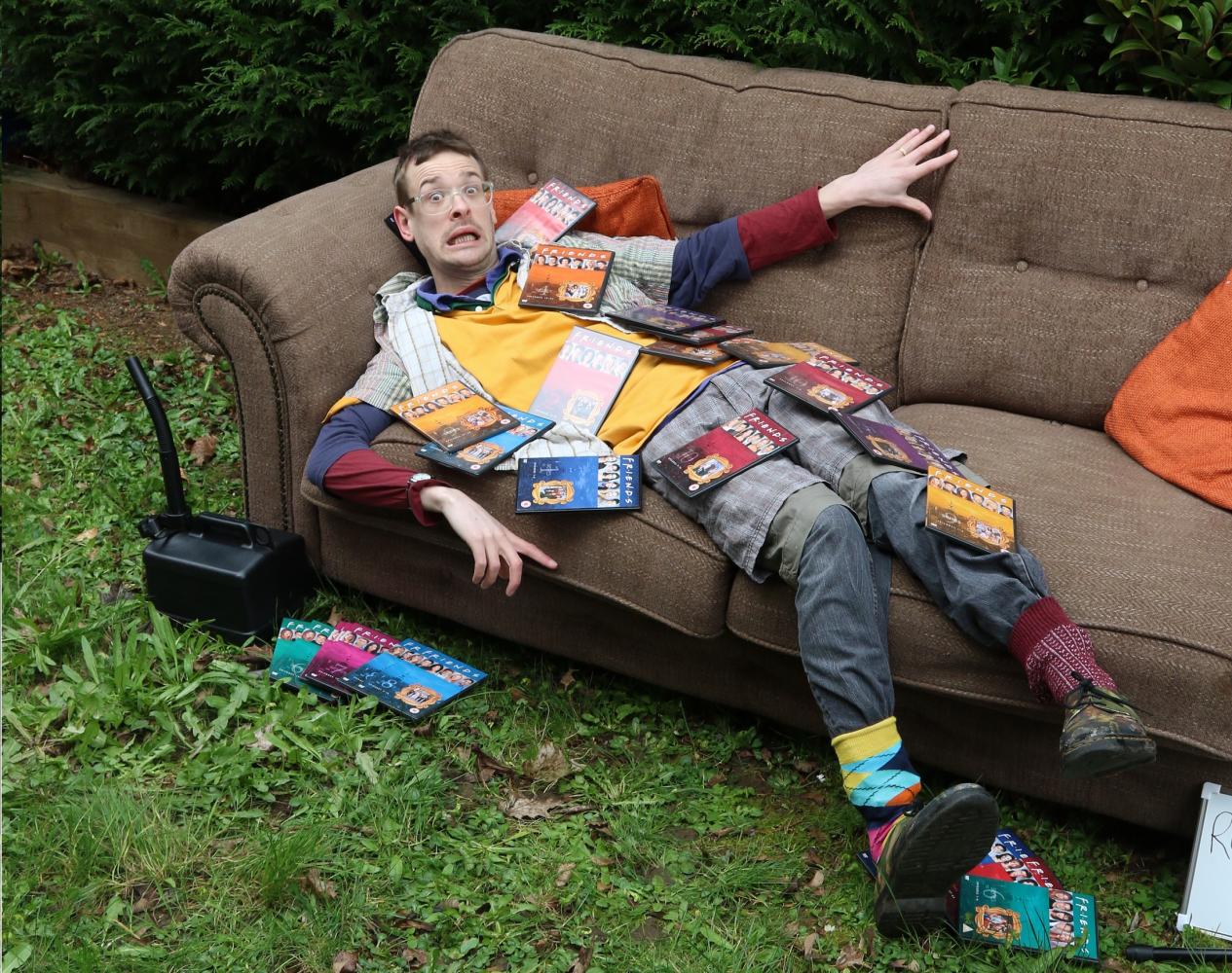Dylan Dodds lies on a sofa, he's covered in Friends DVD's and looks like he's been caught doing something he shouldn't be